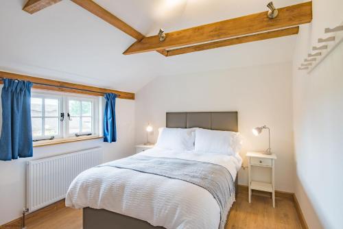 a bedroom with a large bed with blue curtains at Motor House Loft by Bloom Stays in Sandhurst