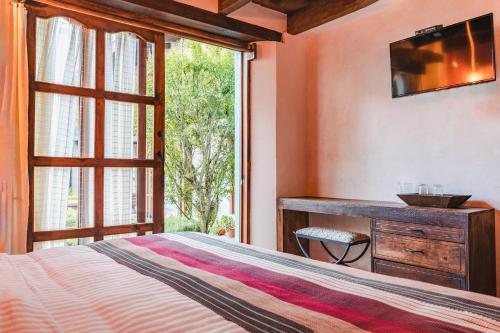 a bedroom with a bed and a desk and a window at Yox Hotel Boutique in San Cristóbal de Las Casas
