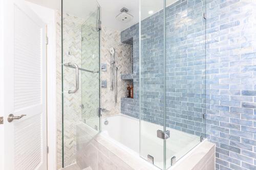 La salle de bains est pourvue d'une baignoire et d'une douche avec du carrelage bleu. dans l'établissement Waikiki Shore 1116 Beachfront, à Honolulu