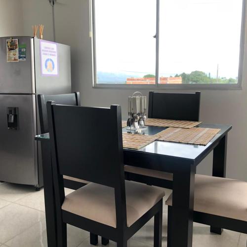 a black dining room table with chairs and a refrigerator at GUADUALES DEL CAFÉ B-409 in Montenegro