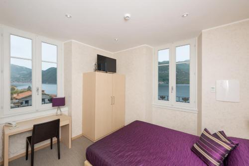 a bedroom with a purple bed and a desk at Hotel Helvetia in Lezzeno