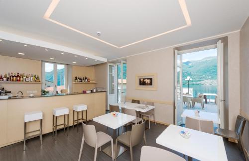 a restaurant with tables and chairs and a bar at Hotel Helvetia in Lezzeno