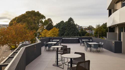 a patio with tables and chairs on a balcony at Rydges Ringwood in Ringwood