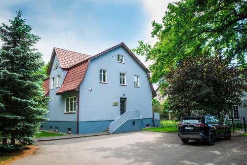 a white house with a car parked in front of it at Liepa in Šilutė