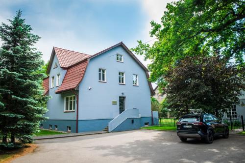 ein weißes Haus mit einem davor geparkt in der Unterkunft Liepa in Šilutė
