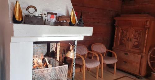 a living room with a fireplace with four chairs at Ønskedrømmen hytteutleie in Brandbu