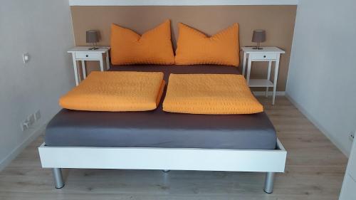 a bed with orange pillows on top of it at Ferienzimmer Arth am See in Arth