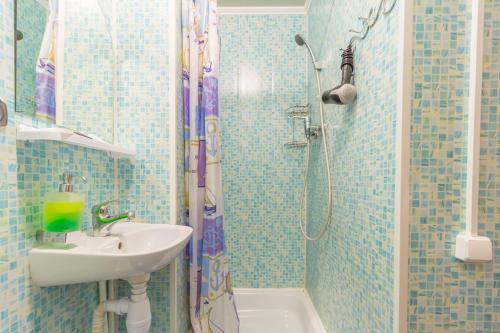 uma casa de banho em azulejos azuis com um lavatório e um chuveiro em Hotel Kolos em Tyumen
