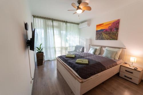 - une chambre avec un lit et un ventilateur de plafond dans l'établissement VIP Apartman Balatonföldvár, à Balatonföldvár