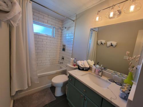 a bathroom with a sink and a toilet and a tub at JoyVeal’s Homey Place in Sechelt