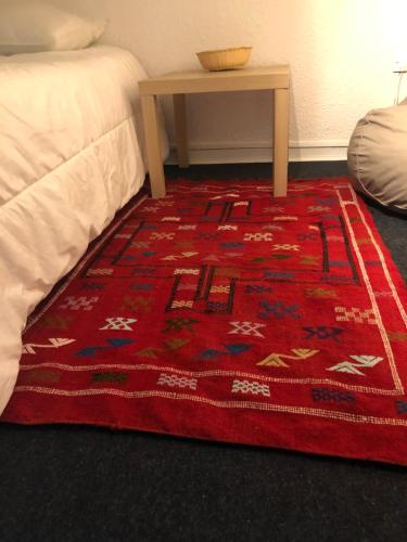 a red rug on the floor next to a bed at studio Bel Air in Saint-Georges-dʼOrques