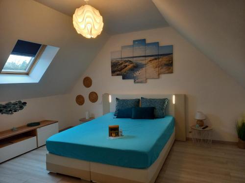 a bedroom with a blue bed in a attic at Hébergement Sarment du Véron Chinon in Beaumont-en-Véron