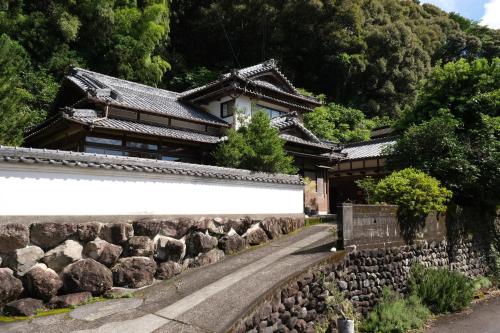 a building with a stone wall next to a road at Shimanto Riverside Hideaway in Shimanto