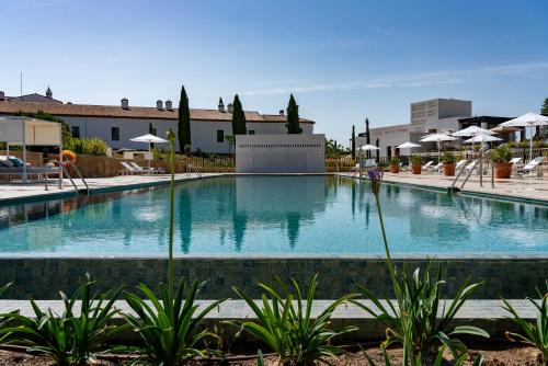 a large swimming pool in a resort with umbrellas at Hospes Palacio de Arenales & Spa in Cáceres