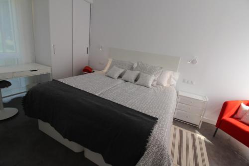 a bedroom with a large bed and a red chair at Apartamento 2 dormitorios con piscina y jardín - Apartamentos Montesomo in Somo