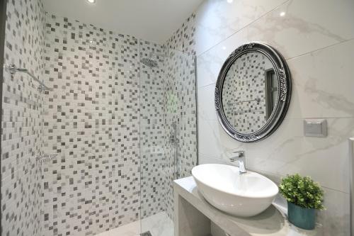 a white bathroom with a sink and a mirror at Elizabeth Studios in Skiathos