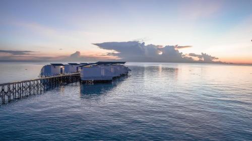 a dock in the water with the sun setting at Arasatu Villas & Sanctuary in Maratua Atoll