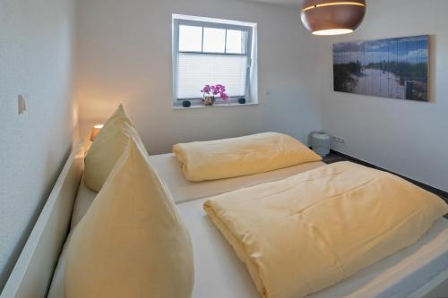 deux lits dans une chambre avec des oreillers jaunes dans l'établissement Küstenkäthe, à Dornumersiel
