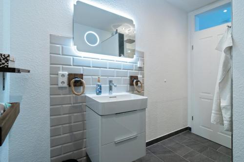 une salle de bain blanche avec un lavabo et un miroir dans l'établissement Küstenkäthe, à Dornumersiel