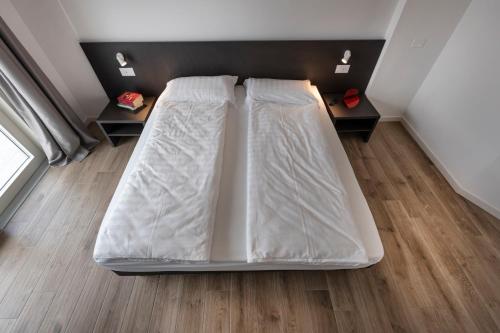 a large bed in a room with wooden floors at Residence Solei Classic & Plus in Brenzone sul Garda