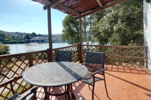 a table and chairs on a deck with a view of a river at Casas Rurales Los Molinos in Sanlúcar de Guadiana
