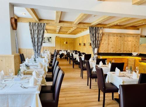 a dining room with white tables and black chairs at Hotel Sonnalp in Kirchberg in Tirol