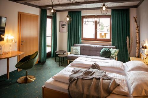 una camera d'albergo con letto e divano di Hotel . Wirtshaus TauernHex a Piesendorf