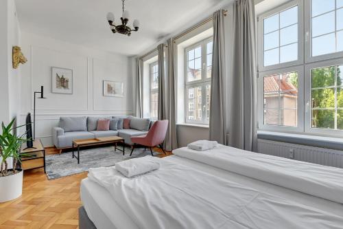 a bedroom with two beds and a couch and windows at Goma Rent - Szeroka Old Town in Gdańsk