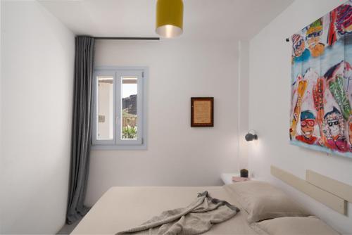 a white bedroom with a bed and a window at Le Grand Blue Villa in Akrotiri