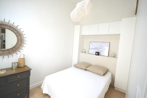 ein weißes Schlafzimmer mit einem Bett und einem Spiegel in der Unterkunft Sweet Jardin des plantes in Paris