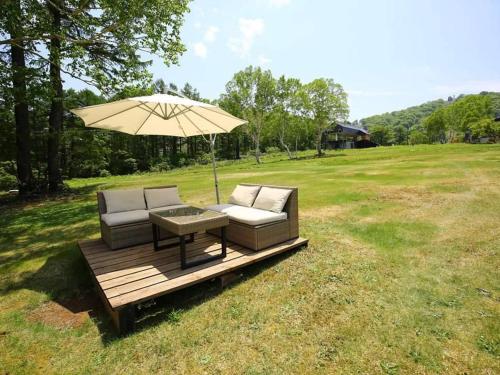 a patio with a table and an umbrella on a field at Oyado Fubuki in Nozawa Onsen