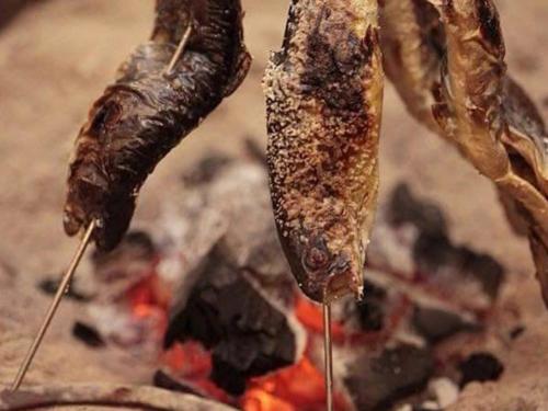 two pieces of meat are cooking over a fire at Oyado Fubuki in Nozawa Onsen