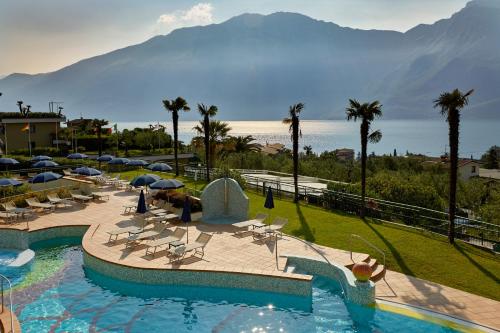 a resort with a swimming pool with a view of a mountain at Hotel Royal Village in Limone sul Garda