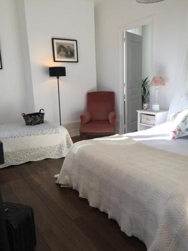 a white bedroom with a bed and a chair at Il était une fois un jardin in Saint-Fargeau