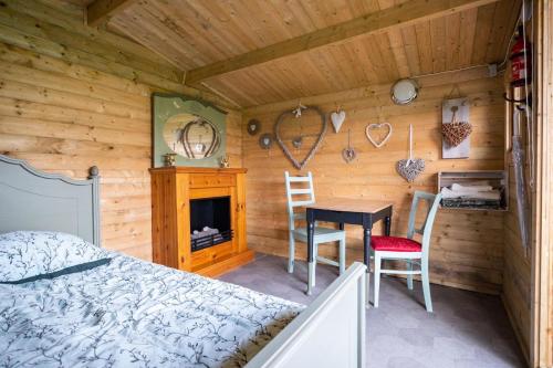 Dormitorio de una cabaña de madera con cama y escritorio en Wijndomein de Vier Ambachten -overnachten in de wijngaard, en Simonshaven