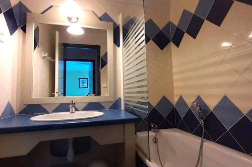 y baño con lavabo, espejo y bañera. en Grand T3 - Terrasse les pieds dans l'eau - Climatisation, en Saint-Raphaël
