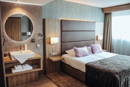
a hotel room with a bed and a mirror at Van der Valk Hotel Breda in Breda
