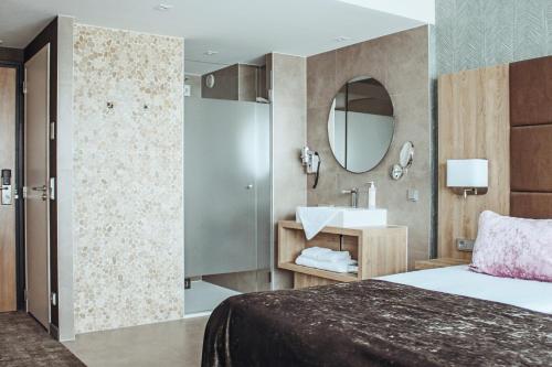 a bedroom with a bed and a sink and a mirror at Van der Valk Hotel Breda in Breda