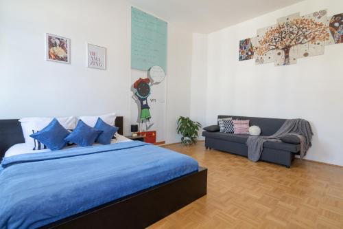 ein Schlafzimmer mit einem blauen Bett und einem Sofa in der Unterkunft Yeshello Apartment near Central Station in Wien
