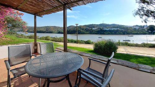 a table and chairs on a patio with a view of a river at Casas Rurales Los Molinos in Sanlúcar de Guadiana