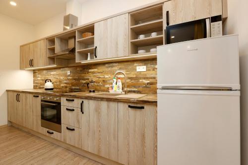 a kitchen with wooden cabinets and a white refrigerator at Apartmány pod Mariánskými schody in Albrechtice v Jizerských horách