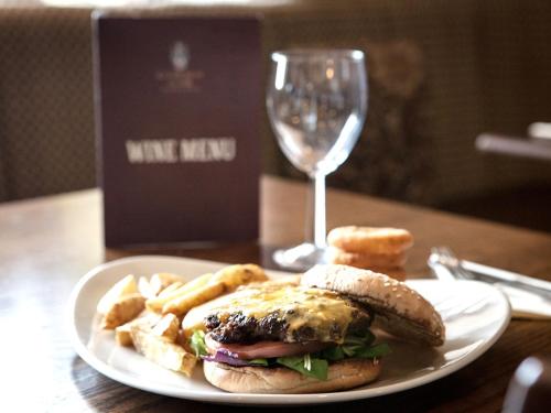 a plate with a sandwich and chips and a glass of wine at The Crewe Arms Hotel in Crewe