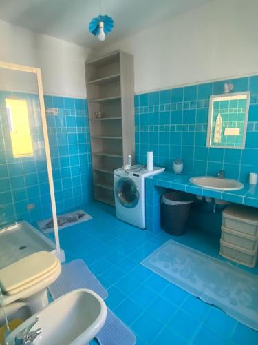 a blue bathroom with a sink and a washing machine at Gerani Quadrilocale in San Teodoro