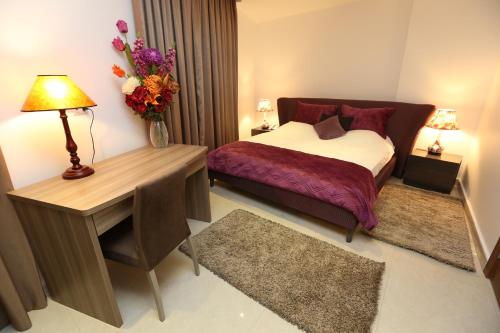 a bedroom with a bed and a desk with a vase of flowers at Delora Hotel and Suites in Chtaura