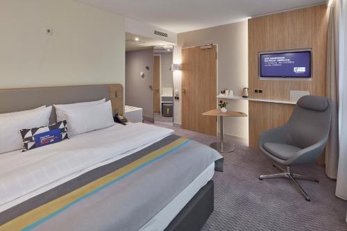 a hotel room with a bed and a chair and a television at Holiday Inn Express - Merzig, an IHG Hotel in Merzig