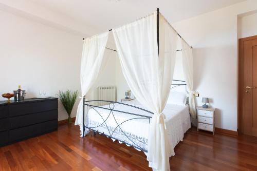 B&B Il giardino degli incanti في سانت إيلبيديو أماري: غرفة نوم مع سرير مظلة مع ستائر بيضاء