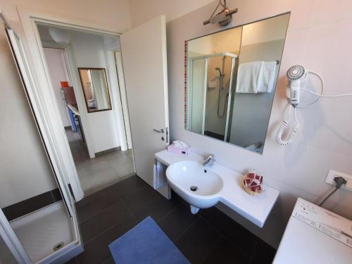 a white bathroom with a sink and a mirror at Residence El Patio in Lido di Jesolo