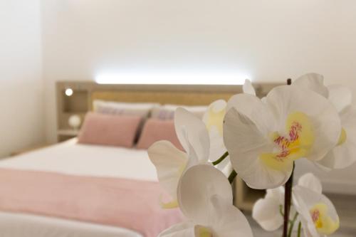 a bedroom with a bed with white flowers in the foreground at Hotel Italia in Cagliari