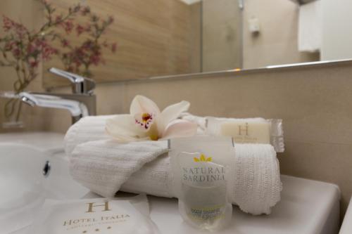 a bathroom with towels and a sink with a mirror at Hotel Italia in Cagliari