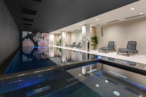 a swimming pool with chairs in a building at Queen's Gambit by Blue Mandarin in Gdańsk